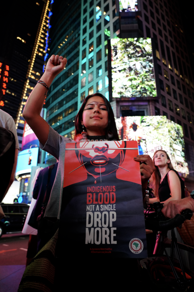 Image Still from film, woman holding poster and fist raised