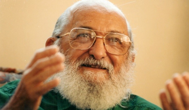 Image of Paulo Freire wearing a green shirt and glasses.