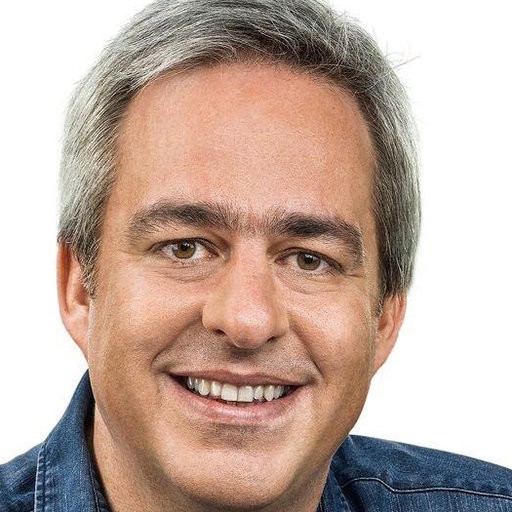 Alexandre Schneider is smiling in a denim shirt against a white background.