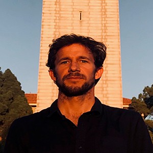 Juan O'Farrell stands in front of a stone tower, wearing a black polo shirt.