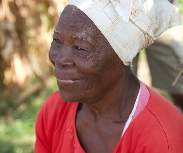 Profile portrait of a woman wearing a bright red shirt and a head wrap