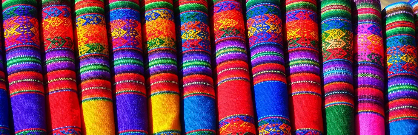 A row of brightly colored, traditional Mexican textiles folded neatly